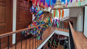 Un escalier avec une rampe, des portes en bois et des décorations en papier aux couleurs vives.