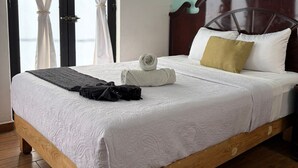 Un lit bien fait, avec un cadre en bois, du linge de lit blanc et une serviette enroulée.
