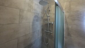 A shower with a handheld showerhead and a wall-mounted faucet. - Nel Paese Room (Skiathos)