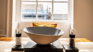 A large bowl on a dark marble stand in front of a window with a view of a construction site. - Stylish and bright City Centre apartment (Exeter)