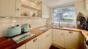 A kitchen with white cabinets, a wooden countertop, a window with blinds, and a built-in oven. - 2 Bed Chalet with Rural Views (Dartmouth)