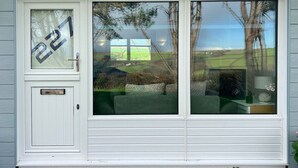 A white house with a number 227 on the door, large windows, and a view of a green landscape. - 2 Bed Chalet with Rural Views (Dartmouth)