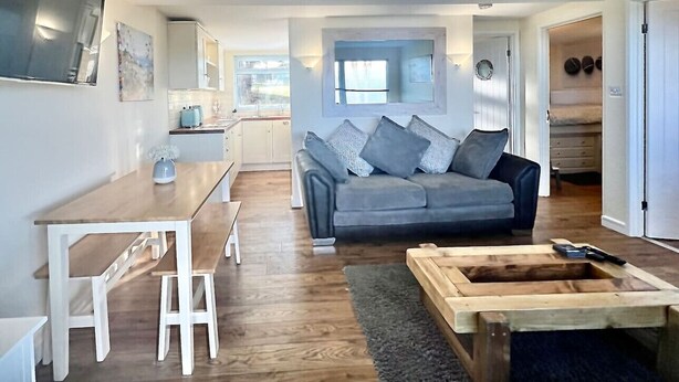 A modern living room with a sofa, coffee table, and dining area. - 2 Bed Chalet with Rural Views (Dartmouth)