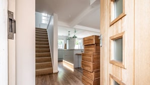 A modern kitchen with wooden cabinets, a staircase, and a view of the outdoors.