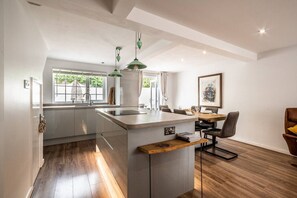 Une cuisine moderne dotée d’un îlot central, de luminaires suspendus et d’un coin repas avec une table et des chaises.