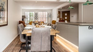 A modern dining area with a wooden table, grey upholstered chairs, and a kitchen island with a built-in sink.