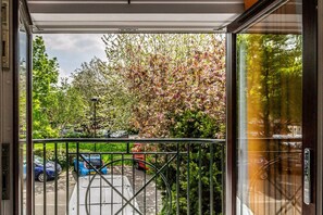 Enter a serene setting with a tree in bloom outside the entrance, where a glass door and metal gate welcome you.