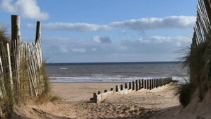 A sandy beach with a wooden fence leading to the ocean. - 2 BR Seaside Flat/ Parks 2 - Garden & Ocean Views (Dawlish)
