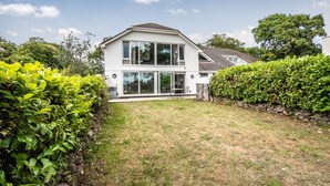 A two-story house with a large glass front and a stone wall on one side. - 2 BR Seaside Flat/ Parks 2 - Garden & Ocean Views (Dawlish)