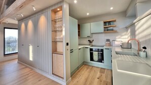 Une cuisine moderne dotée de meubles de rangement intégrés, d’un plan de travail et d’une fenêtre donnant sur un balcon.
