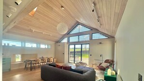 Un vaste espace de vie doté d’un haut plafond, de poutres en bois et de grandes fenêtres.