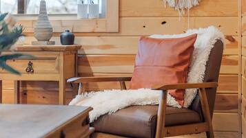 A wooden cabin interior with a wooden chair, a small table, and a lamp.