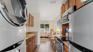 A kitchen with a stainless steel refrigerator, a built-in oven, and a washing machine.