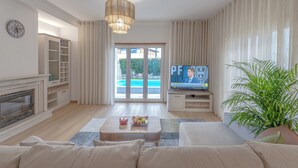 Uma sala de estar moderna com lareira, televisão e vista para o exterior.
