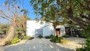 A white building with a gated entrance, surrounded by greenery and a paved area. - Choose a family vacation rental in Morondava! (Morondava)