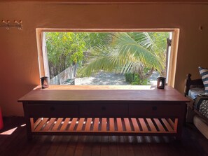 A wooden bench with a window view of a garden with palm trees. - Choose a family vacation rental in Morondava! (Morondava)