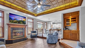 A spacious living room with a fireplace, wooden flooring, and a ceiling fan.