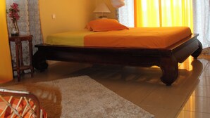 Un dormitorio con una cama, una mesita de noche, una lámpara, un cuadro y cortinas.