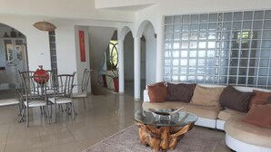 Una sala de estar moderna con una mesa de centro de vidrio, un sofá color beige y un comedor con sillas y una mesa.