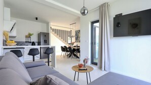 A modern living room with a grey sofa, a small wooden table with a remote control, and a TV mounted on the wall. - Villa Cvit Mediterana with heated pool (Poljica-Brig)
