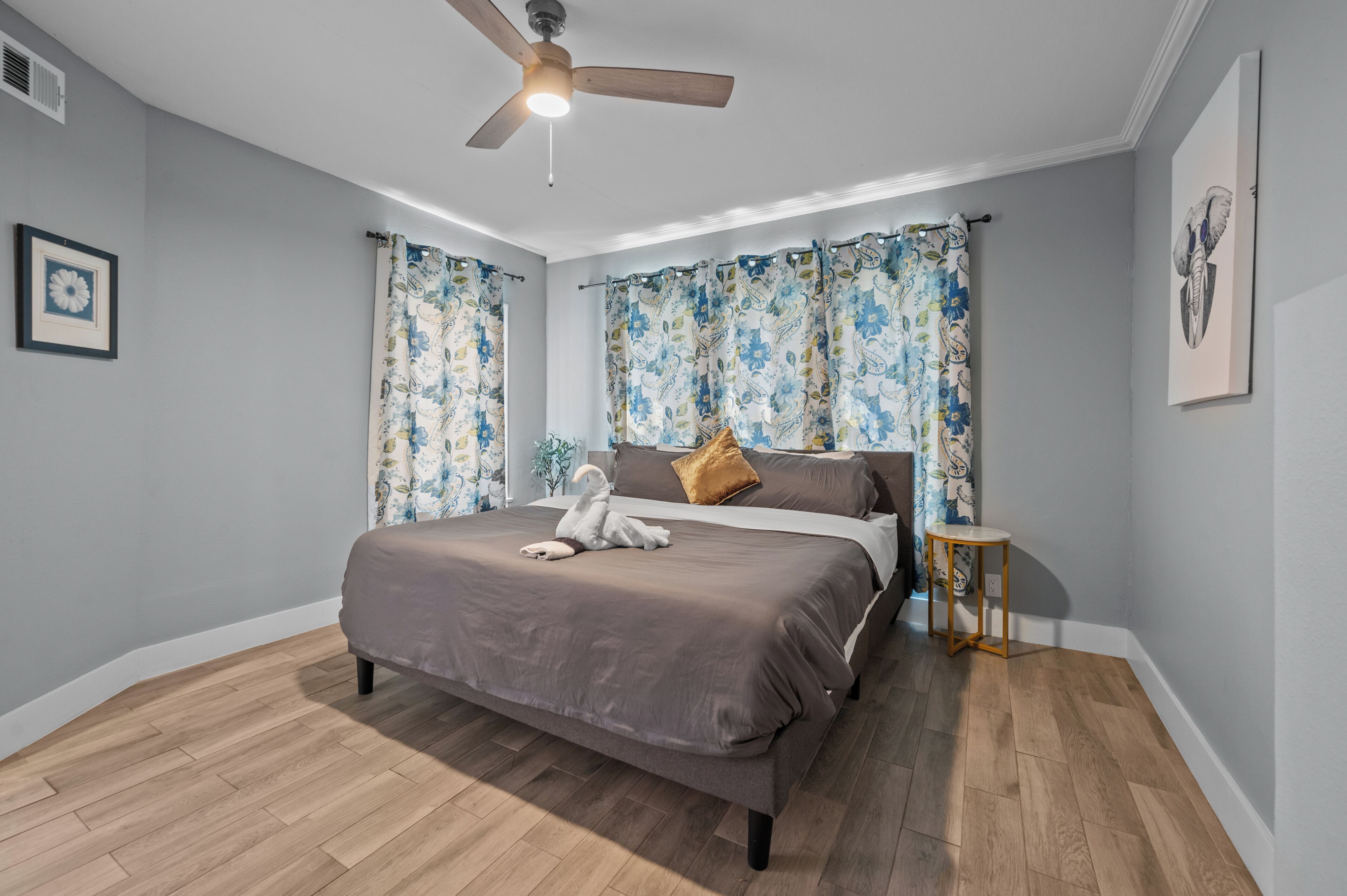 Un dormitorio con cama, ventilador de techo y una mesita.