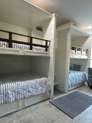 Una habitación con literas, una alfombra estampada y una escalera.