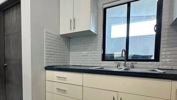 Eine moderne Küche mit weißen Schränken, einer schwarzen Arbeitsplatte und einem Fenster über der Spüle.
