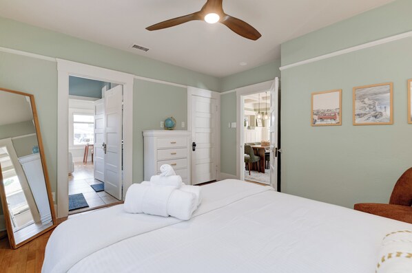 Un dormitorio con cama, ventilador de techo, cómoda y espejo.