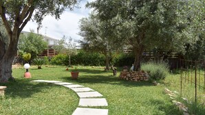Un jardín con un sendero de piedra, árboles y una valla.