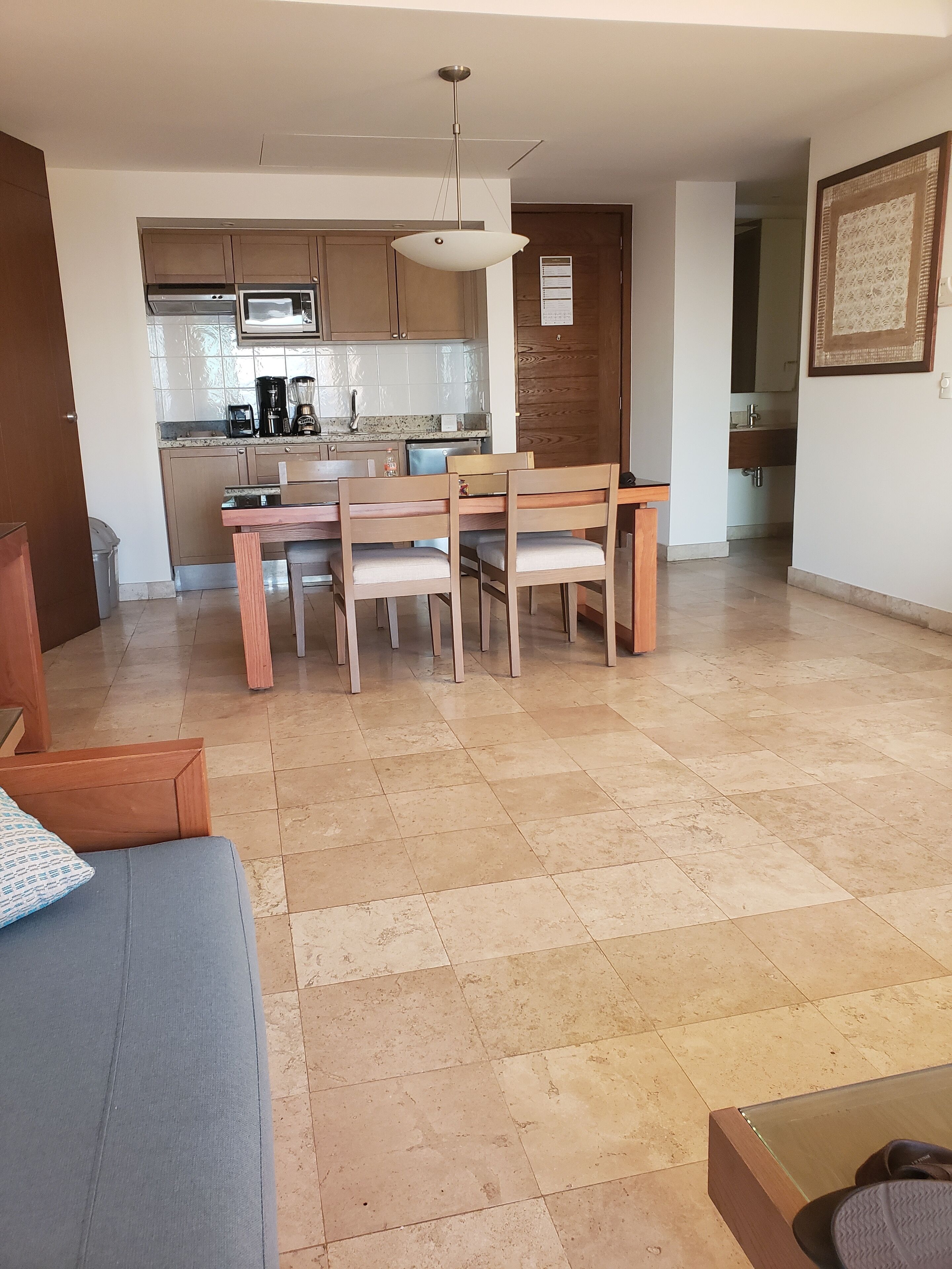 Een moderne woonkamer met een bank, een eettafel met stoelen en een keuken met apparatuur en kasten.