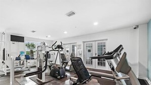 A modern gym with various exercise equipment, large windows, and a clean, white interior. - Grand Caribbean 312 2 Bed 2 Bath - Great View! (Orange Beach)