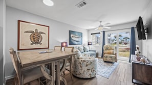 A dining area with a wooden table and chairs, a sofa, and a ceiling fan. - Gulf Shores Plantation 4112 Ft Morgan Oasis (Gulf Shores)