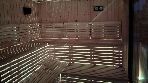 Un sauna avec des bancs en bois et un plafond doté de luminaires encastrés.