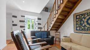 A living room with a staircase, a sofa, a chair, and a rug. - Holiday Home 'Casa Do Caseiro' with Mountain View, Private Garden and Wi-Fi (Ponta Delgada)