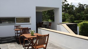 A modern outdoor patio with a table and chairs, a potted plant, and a view of the surrounding greenery. - Holiday Home 'Casa Do Caseiro' with Mountain View, Private Garden and Wi-Fi (Ponta Delgada)