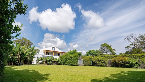 A house with a large lawn, surrounded by trees and a clear sky. - Holiday Home 'Casa Do Caseiro' with Mountain View, Private Garden and Wi-Fi (Ponta Delgada)