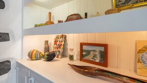 A white shelf with decorative items, a framed painting, and a wooden boat. - Holiday Home 'Casa Do Caseiro' with Mountain View, Private Garden and Wi-Fi (Ponta Delgada)