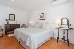 Une chambre à coucher comprenant un lit, une commode, une table de chevet et un miroir fixé au mur.