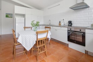 Une cuisine compacte avec des meubles blancs, un four encastré et une table à manger avec des chaises.