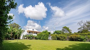 Una casa con un ampio prato, circondata da alberi e un cielo sereno.