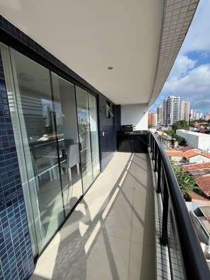 A balcony with a glass door, a tiled floor, and a view of the cityscape. - Apartment in Belém - Umarizal (Umarizal Belém)