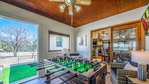 Un salón espacioso con mesa de fútbol, comedor y un gran ventanal con vistas al exterior.