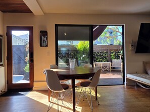 A dining area with a table and chairs, a sliding glass door leading to an outdoor patio, and a bench.