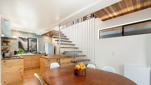 Une cuisine moderne avec des meubles en bois, une cuisinière encastrée et un coin repas comprenant une table et des chaises en bois.