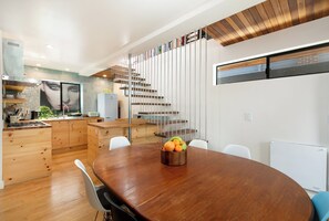 A modern kitchen with wooden cabinets, a built-in stove, and a dining area with a wooden table and chairs.