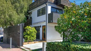 Una moderna casa a due piani con tetto piatto, porta del garage a vista e ingresso principale con porta.