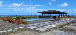 Un área de piscina con una zona de estar cubierta y vista al océano.
