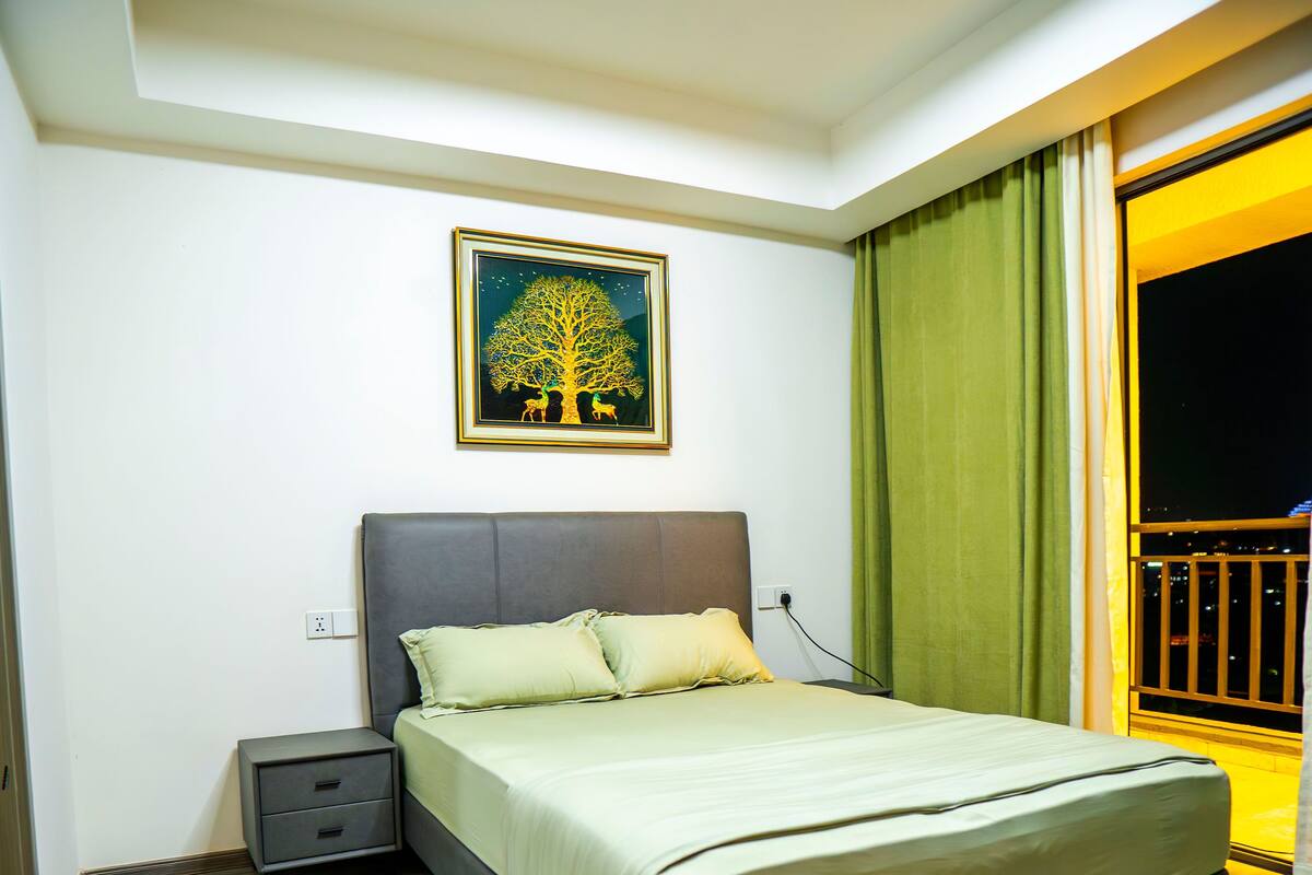 A bedroom with a bed, nightstand, and a painting on the wall.
