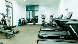Et fitnesscenter med løbebånd, crosstrainere og forskelligt træningsudstyr.