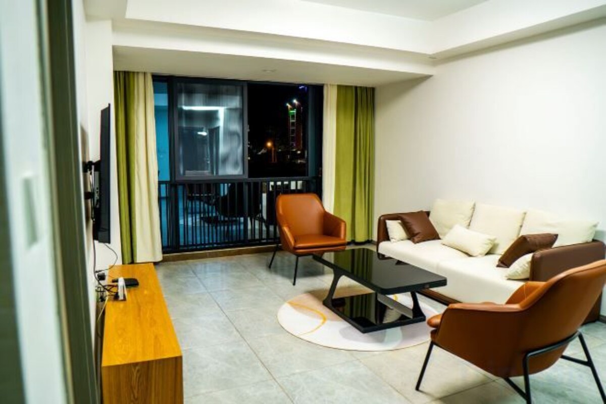 A modern living room with a sofa, armchairs, a coffee table, and a TV.